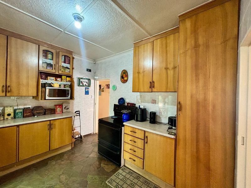A functional kitchen featuring traditional wooden cabinetry, laminate countertops, and a freestanding stove, offering a classic layout with ample storage space.