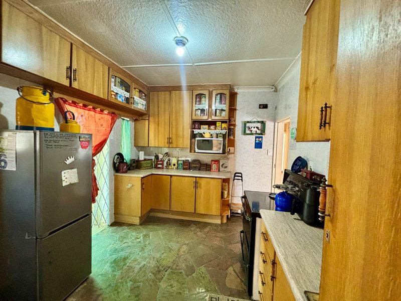A functional kitchen featuring wood-tone cabinetry, stone-look countertops, and stone tile flooring, offering a traditional layout with ample storage space.