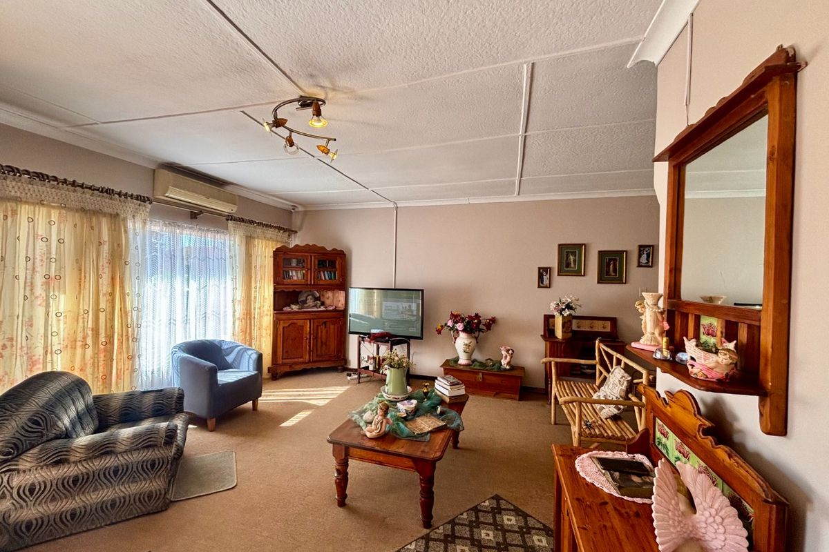 A spacious living room featuring a split-system air conditioner, tiled ceiling, and large sliding glass doors providing natural light.