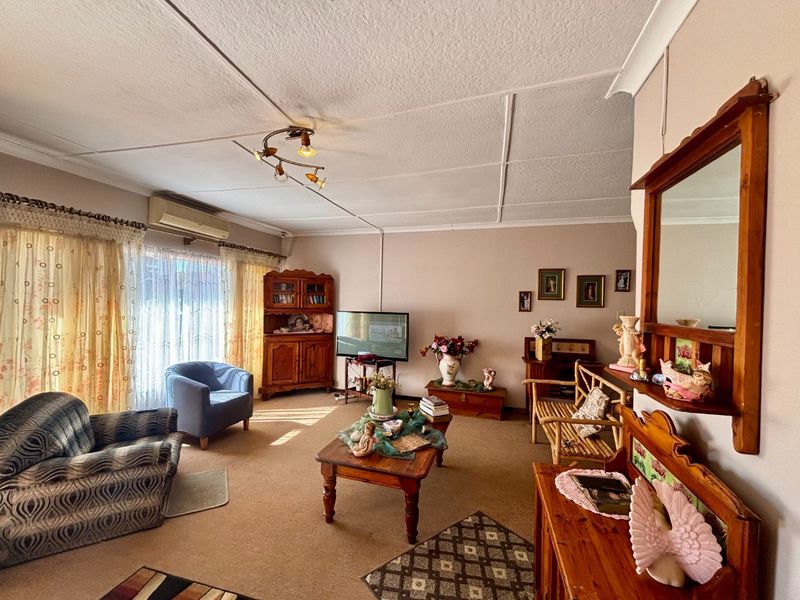A spacious living room featuring a split-system air conditioner, tiled ceiling, and large sliding glass doors providing natural light.