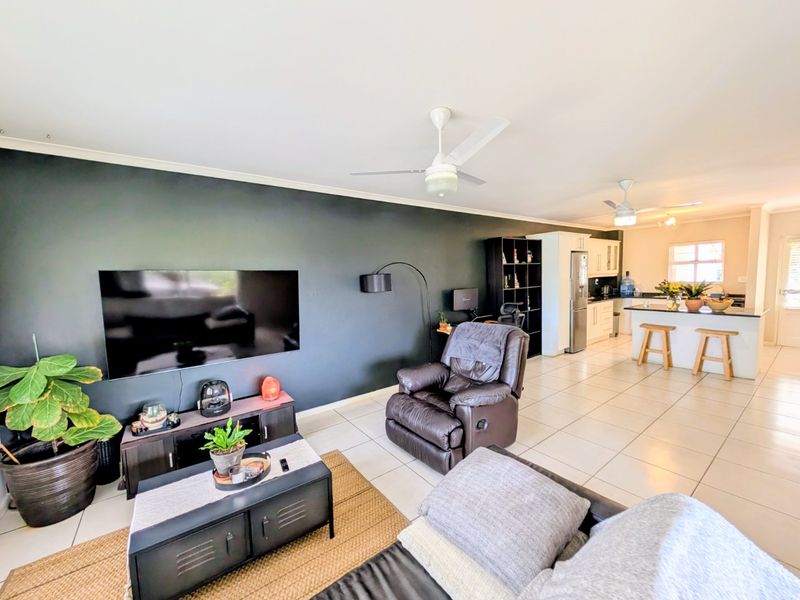 Spacious open-plan living area featuring tiled floors, ceiling fans, and a modern kitchen with a central island and ample cabinetry.
