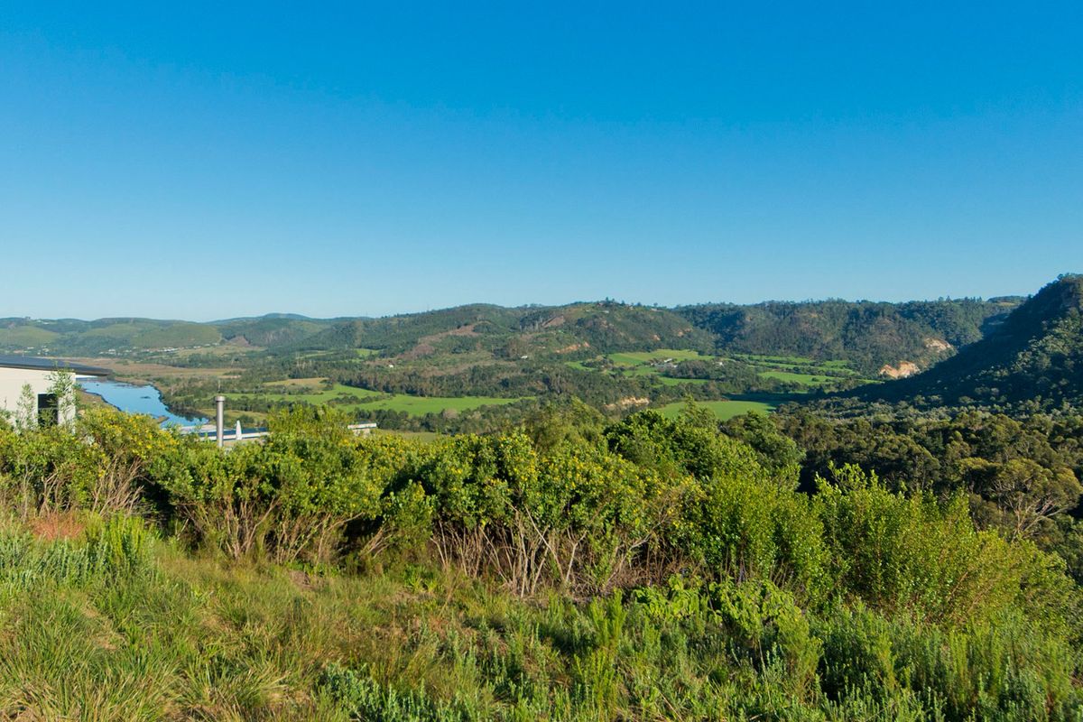 A scenic elevated view overlooking a lush green valley, rolling hills, and a winding river, showcasing the natural landscape of the property.