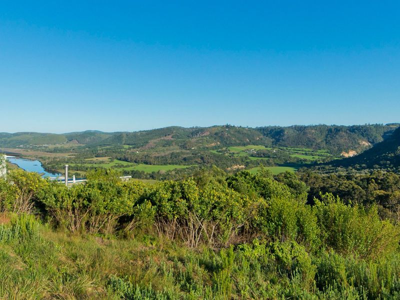 A scenic elevated view overlooking a lush green valley, rolling hills, and a winding river, showcasing the natural landscape of the property.