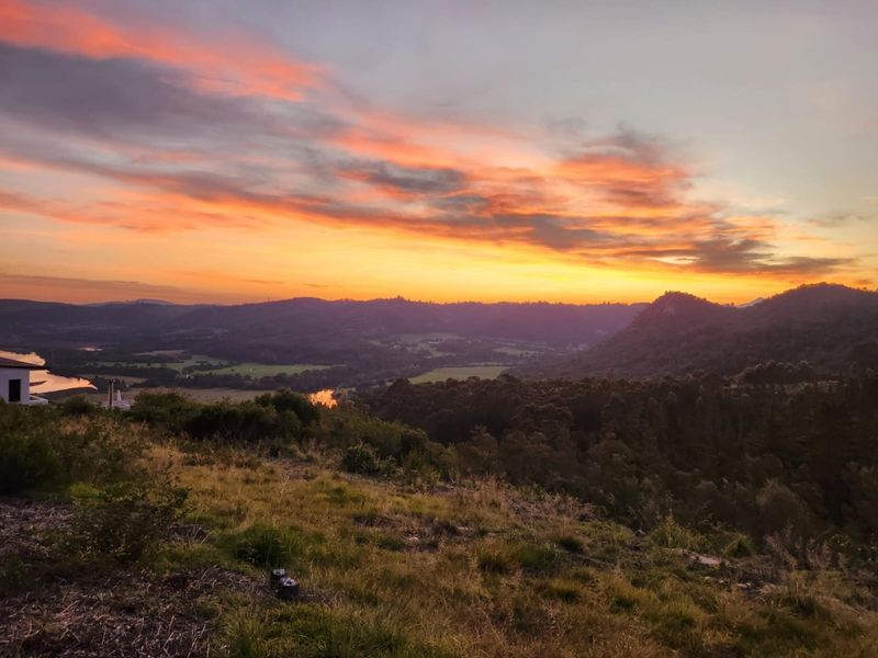 A scenic sunset view overlooking the rolling hills, valley, and river, showcasing the natural landscape surrounding the vacant residential land.