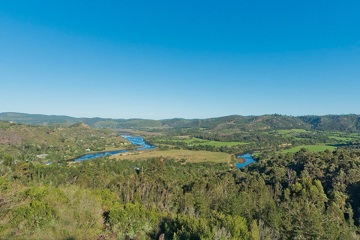 A scenic elevated view overlooking a winding river, lush green valley, and surrounding hills, showcasing the natural landscape of the property.
