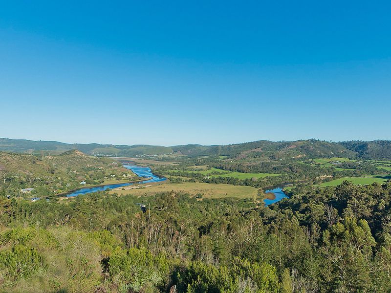 A scenic elevated view overlooking a winding river, lush green valley, and surrounding hills, showcasing the natural landscape of the property.