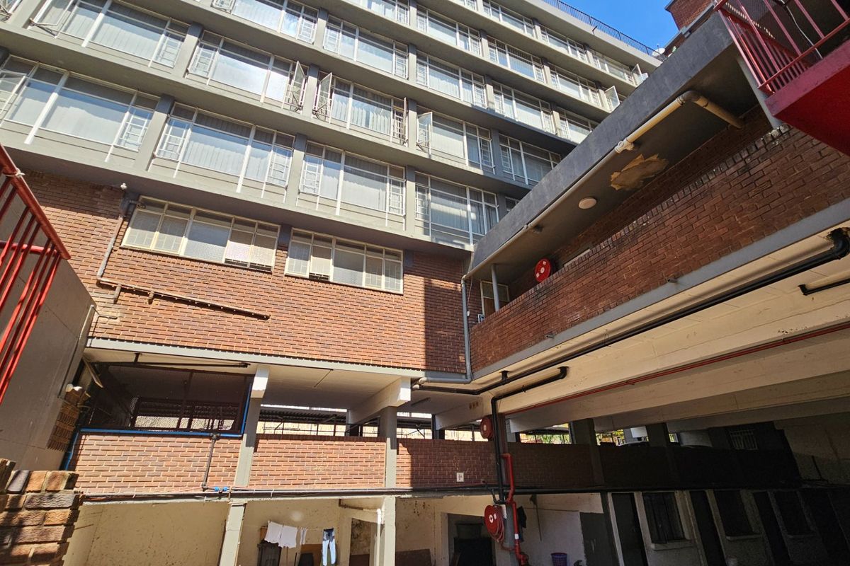 View of the rear exterior facade of a multi-story commercial building featuring brickwork, metal railings, and exposed structural concrete elements.