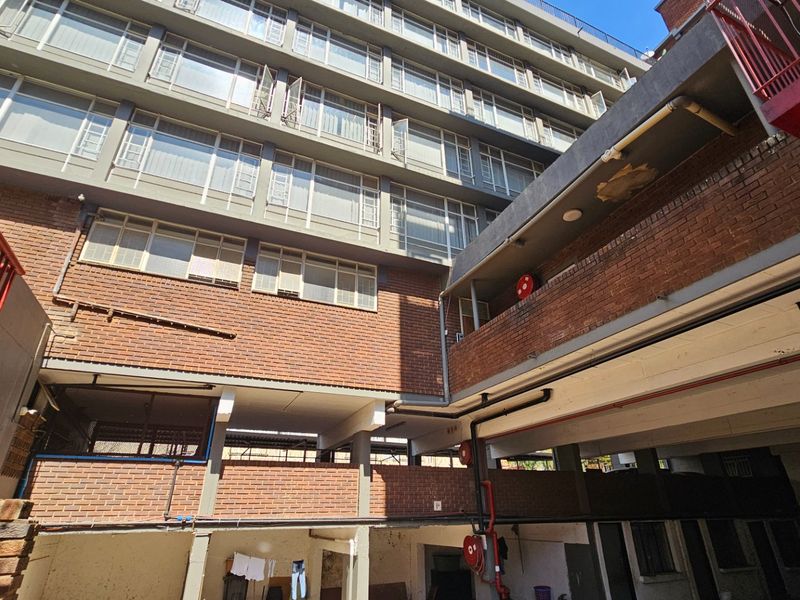View of the rear exterior facade of a multi-story commercial building featuring brickwork, metal railings, and exposed structural concrete elements.