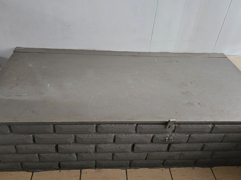 A utility area featuring a brick-based structure with a flat top surface and tiled flooring, suitable for storage or functional use.