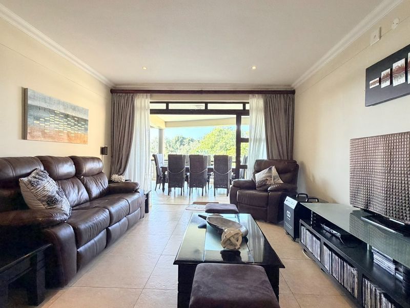 Spacious living room featuring tiled flooring, recessed lighting, and large sliding glass doors that open onto a covered patio area.