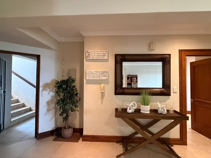An inviting apartment entryway featuring tiled flooring, wooden door frames, and a secure entrance gate leading to a staircase.