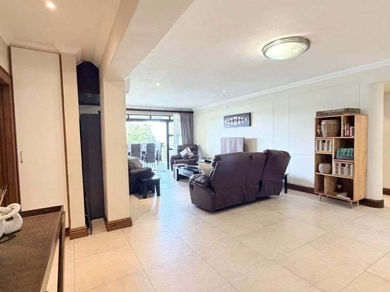 Spacious open-plan living area featuring neutral tiled flooring, recessed lighting, and large sliding glass doors leading to an outdoor patio space.