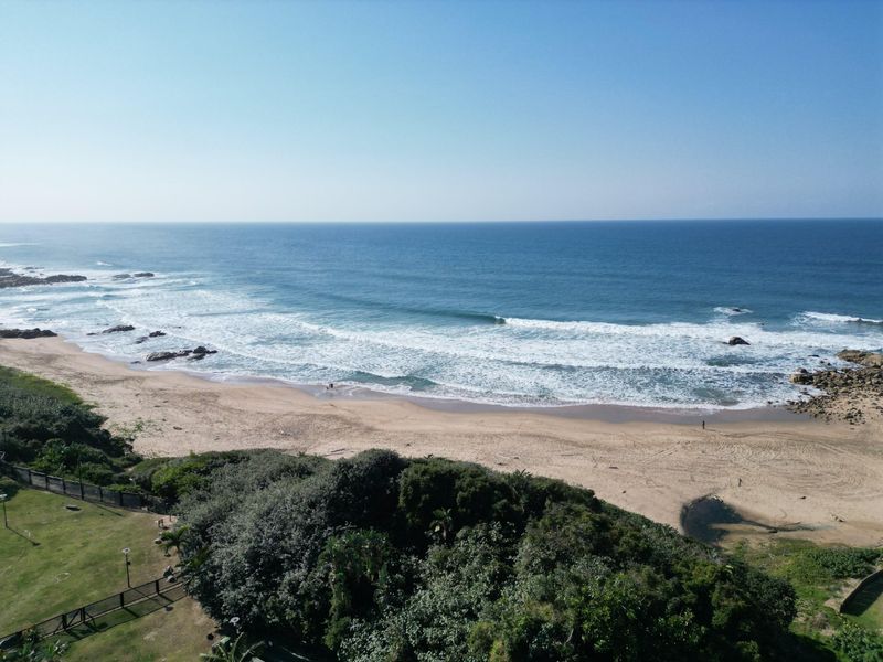 A scenic aerial view of the coastline featuring a sandy beach and the ocean.