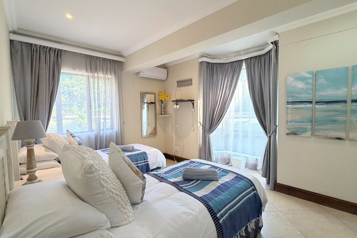 A bright and well-maintained bedroom featuring tiled flooring, split-system air conditioning, and large windows with curtain treatments.