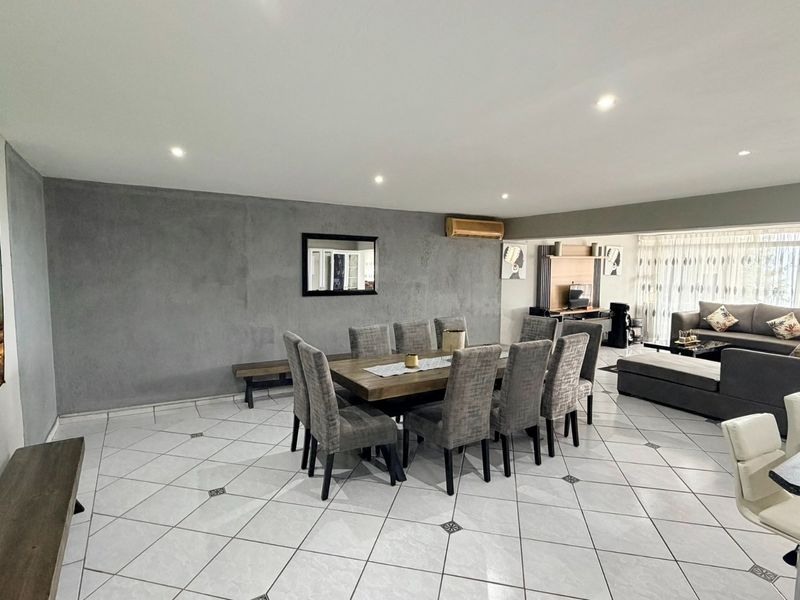 Spacious open-plan living and dining area featuring tiled flooring, recessed lighting, and large sliding doors providing natural light and outdoor access.