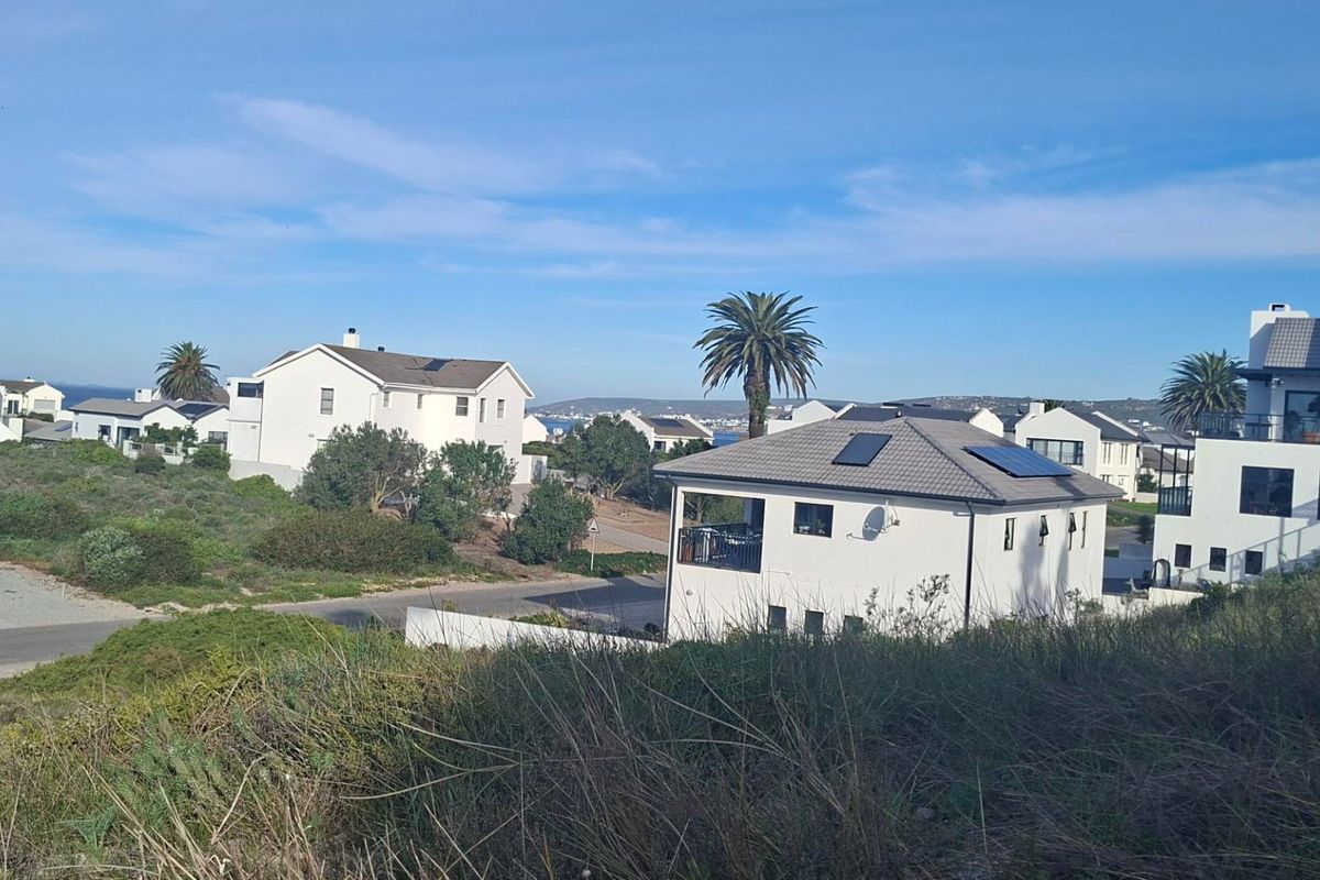 An elevated view of a residential neighborhood featuring modern homes with tiled roofs and solar panels under a clear blue sky.