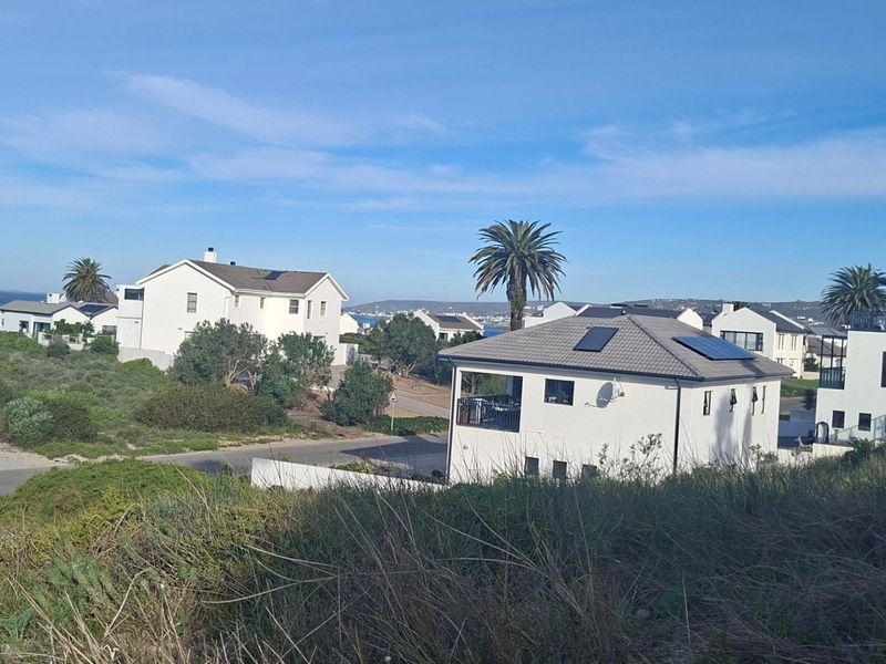 An elevated view of a residential neighborhood featuring modern homes with tiled roofs and solar panels under a clear blue sky.