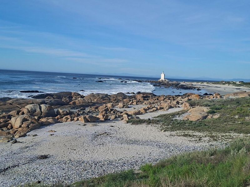 A scenic coastal view featuring a rocky shoreline, sandy beach, and ocean horizon, highlighting the natural landscape of the property location.