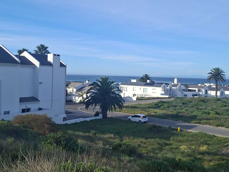 A scenic elevated view overlooking a coastal residential estate with surrounding natural vegetation and ocean views in the distance.