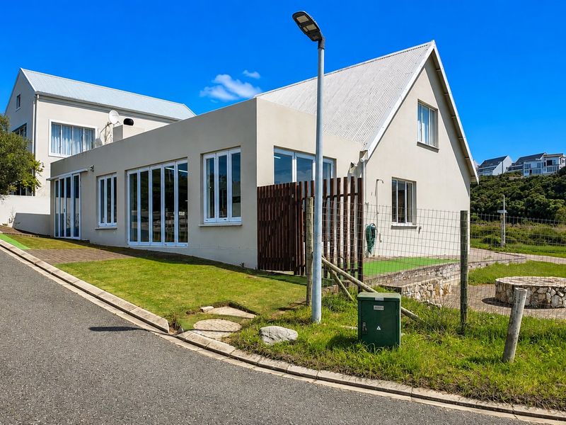 A modern residential exterior featuring a corrugated metal roof, large bi-fold doors, and a well-maintained lawn area.