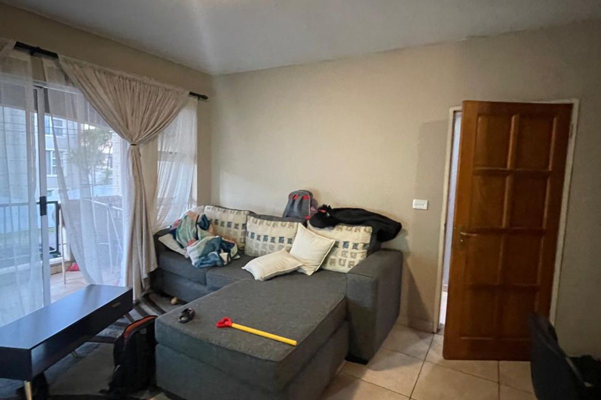 A living room featuring tiled flooring, a sliding glass door leading to a balcony, and a wooden interior door.