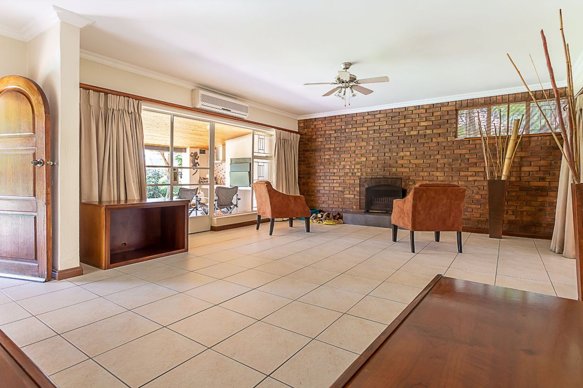 Spacious living room featuring a brick accent wall, built-in fireplace, tiled flooring, and direct access to the outdoor patio area.