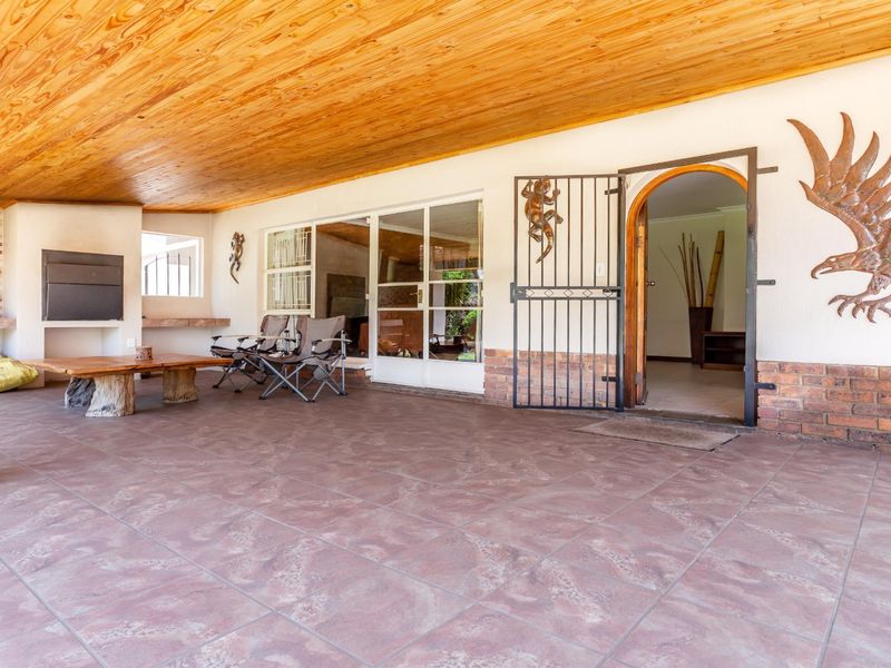 Spacious covered patio featuring a timber ceiling, tiled flooring, and a built-in braai area, providing an ideal space for outdoor entertaining.