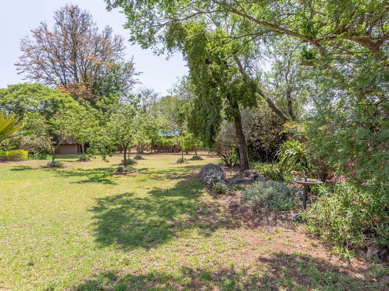 A spacious, well-established garden featuring mature trees, expansive lawn areas, and established garden beds, offering a peaceful outdoor setting.