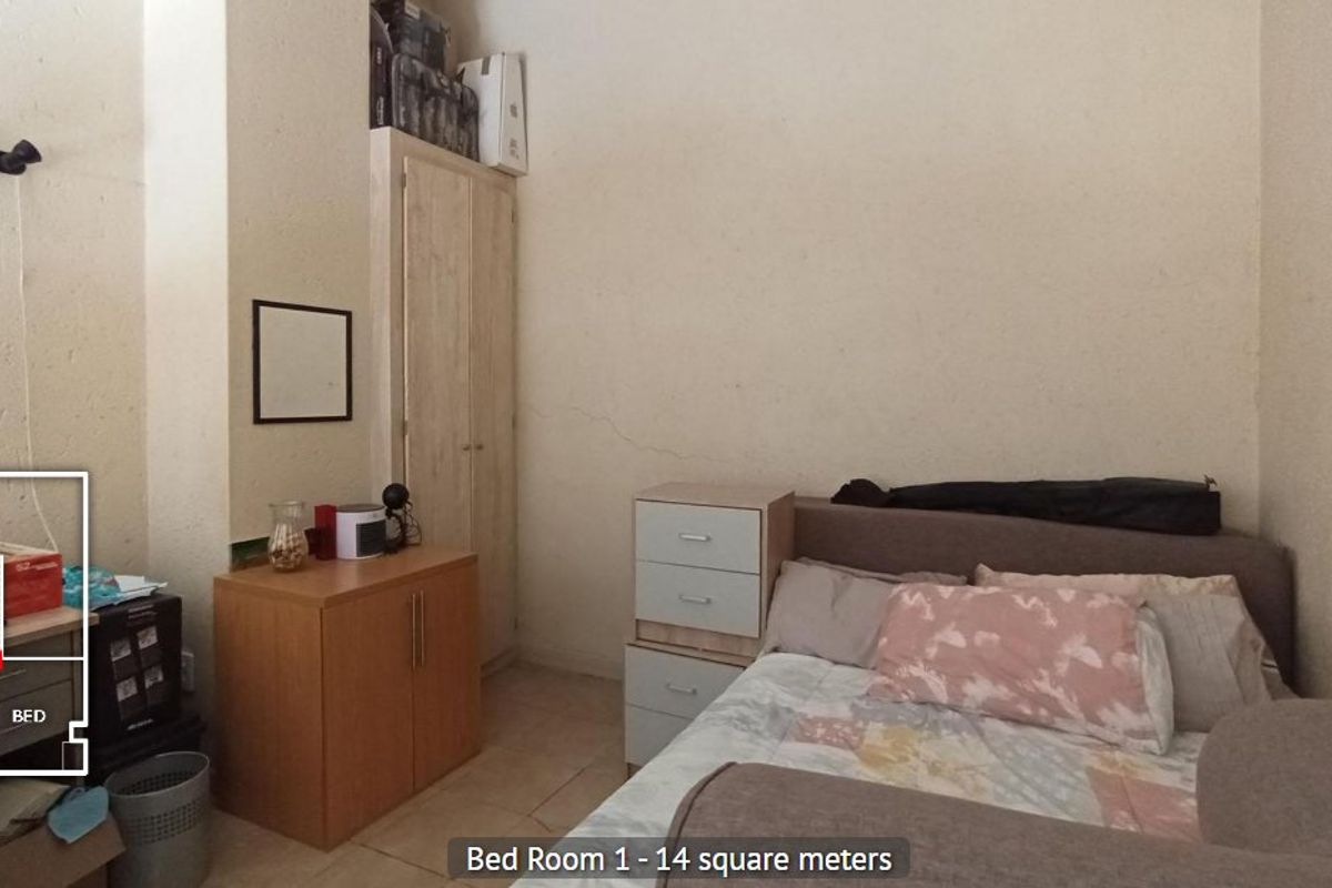 A bedroom featuring tiled flooring and a built-in wardrobe, showing signs of wall plaster cracking.