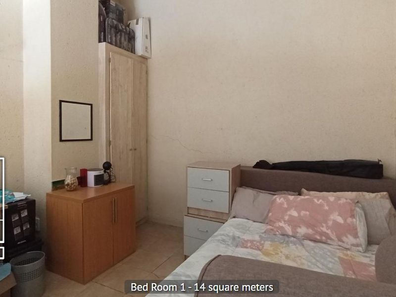 A bedroom featuring tiled flooring and a built-in wardrobe, showing signs of wall plaster cracking.