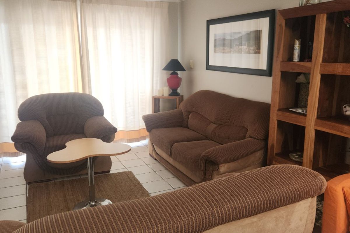 A living room featuring tiled flooring, recessed downlighting, and a sliding glass door providing natural light.