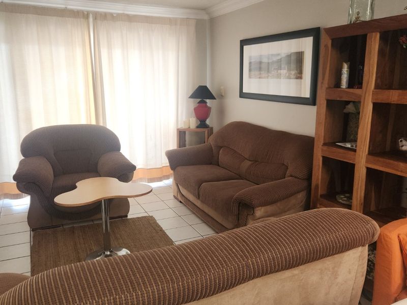A living room featuring tiled flooring, recessed downlighting, and a sliding glass door providing natural light.