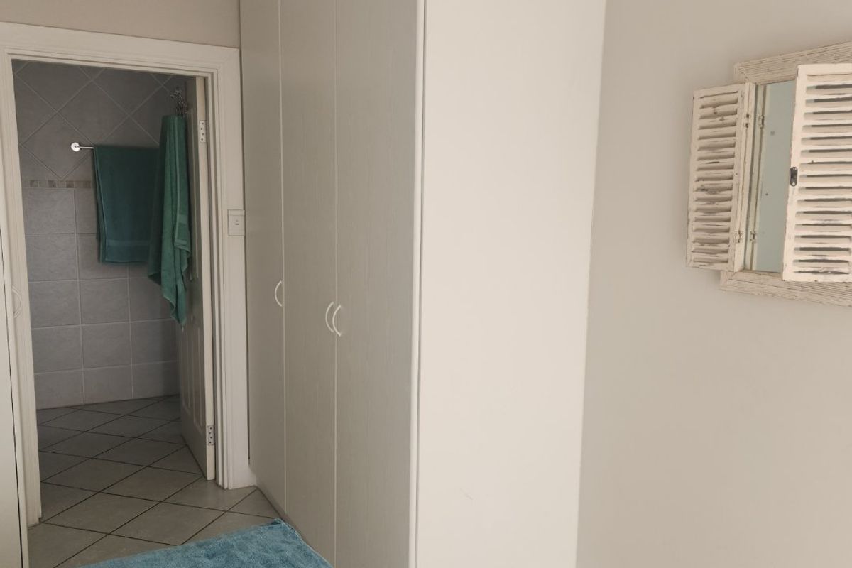 A bedroom featuring built-in cupboards, crown molding, and recessed lighting, with an adjoining tiled bathroom visible through the doorway.