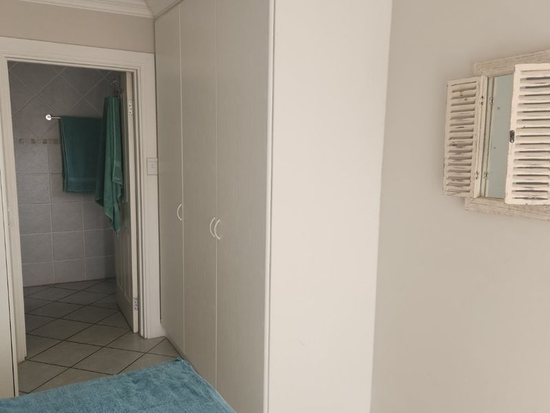 A bedroom featuring built-in cupboards, crown molding, and recessed lighting, with an adjoining tiled bathroom visible through the doorway.