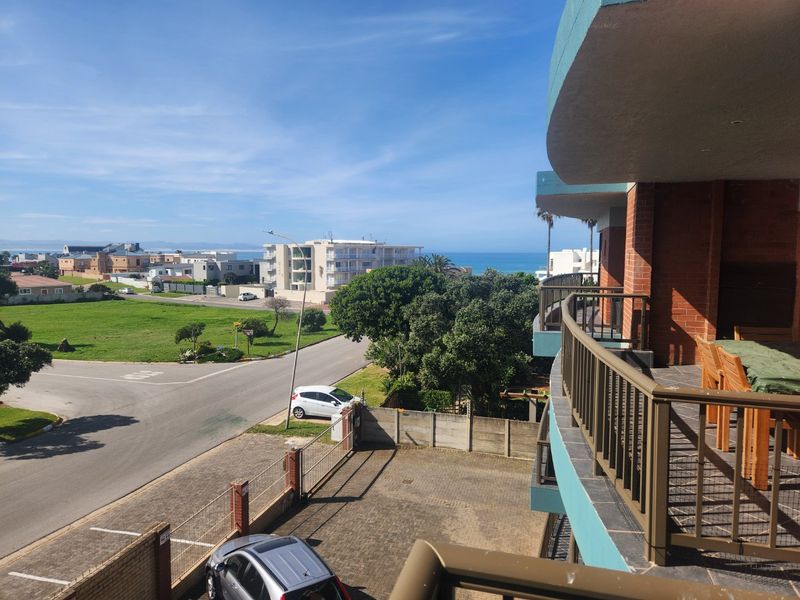 Elevated view from a balcony overlooking the surrounding neighborhood, street, and distant ocean coastline.