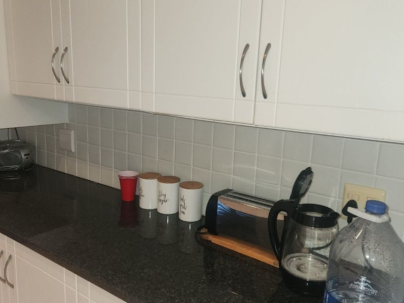 A clean kitchen area featuring white shaker-style cabinetry, dark granite countertops, and a neutral tiled backsplash.