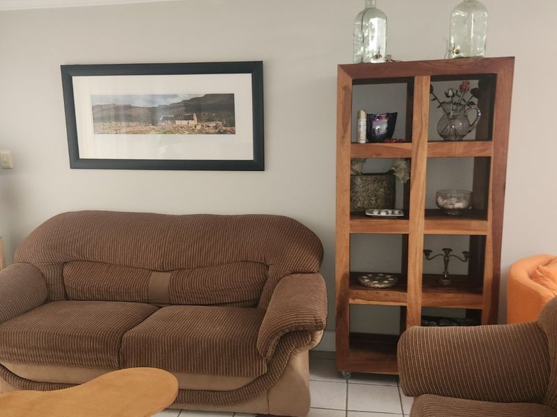A living room area featuring neutral wall tones, tiled flooring, and decorative coving, providing a functional space for relaxation.