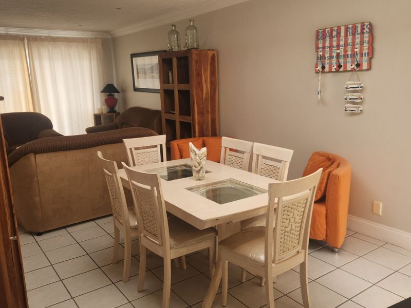 Open plan living and dining area featuring ceramic floor tiles, a skylight, and coved ceiling details.