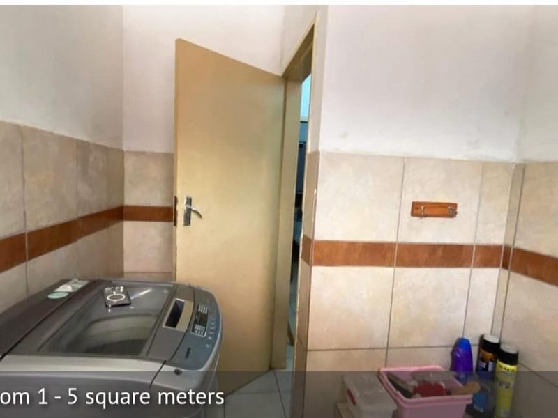 A functional laundry area featuring tiled walls and flooring, providing a practical space for washing appliances and utility tasks.