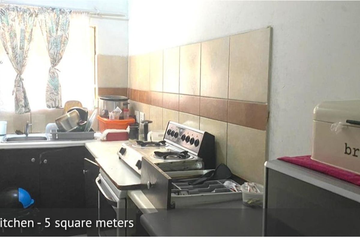 Compact kitchen featuring a stainless steel sink, tiled splashback, and a freestanding stove with laminate countertops and built-in cabinetry.