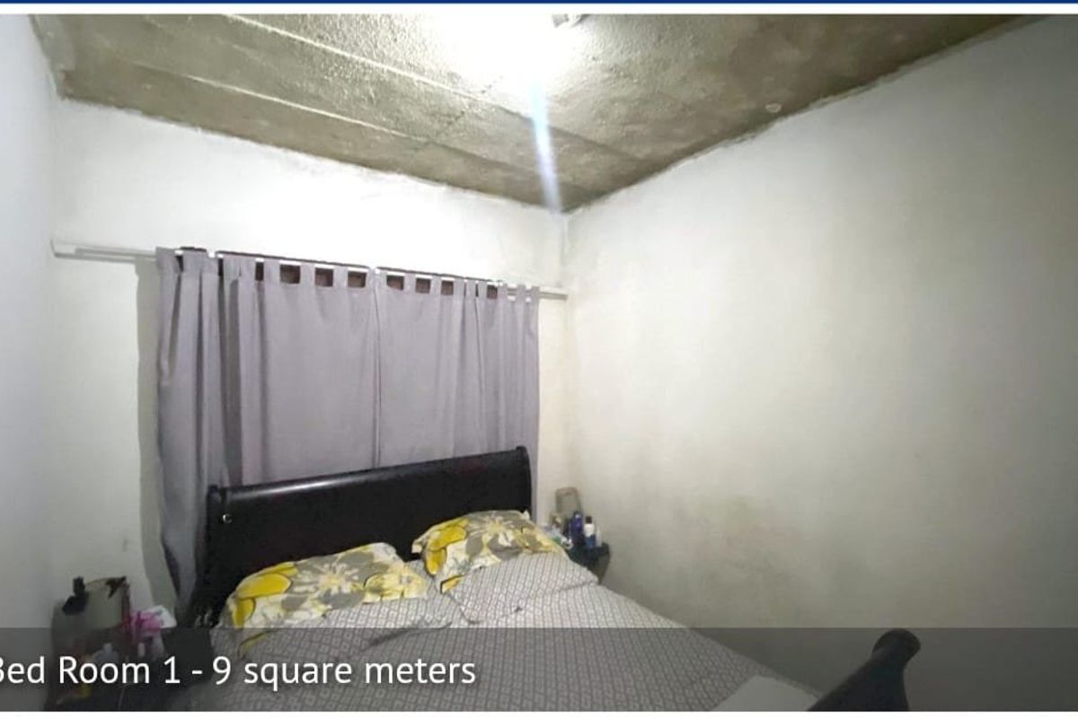 A small bedroom featuring an unfinished concrete ceiling and plain walls, requiring cosmetic updates to improve the overall finish and appeal.