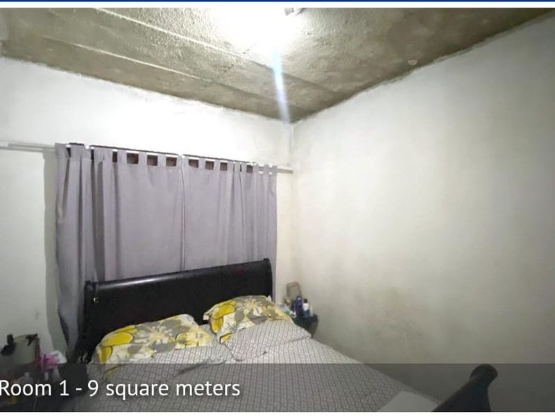 A small bedroom featuring an unfinished concrete ceiling and plain walls, requiring cosmetic updates to improve the overall finish and appeal.