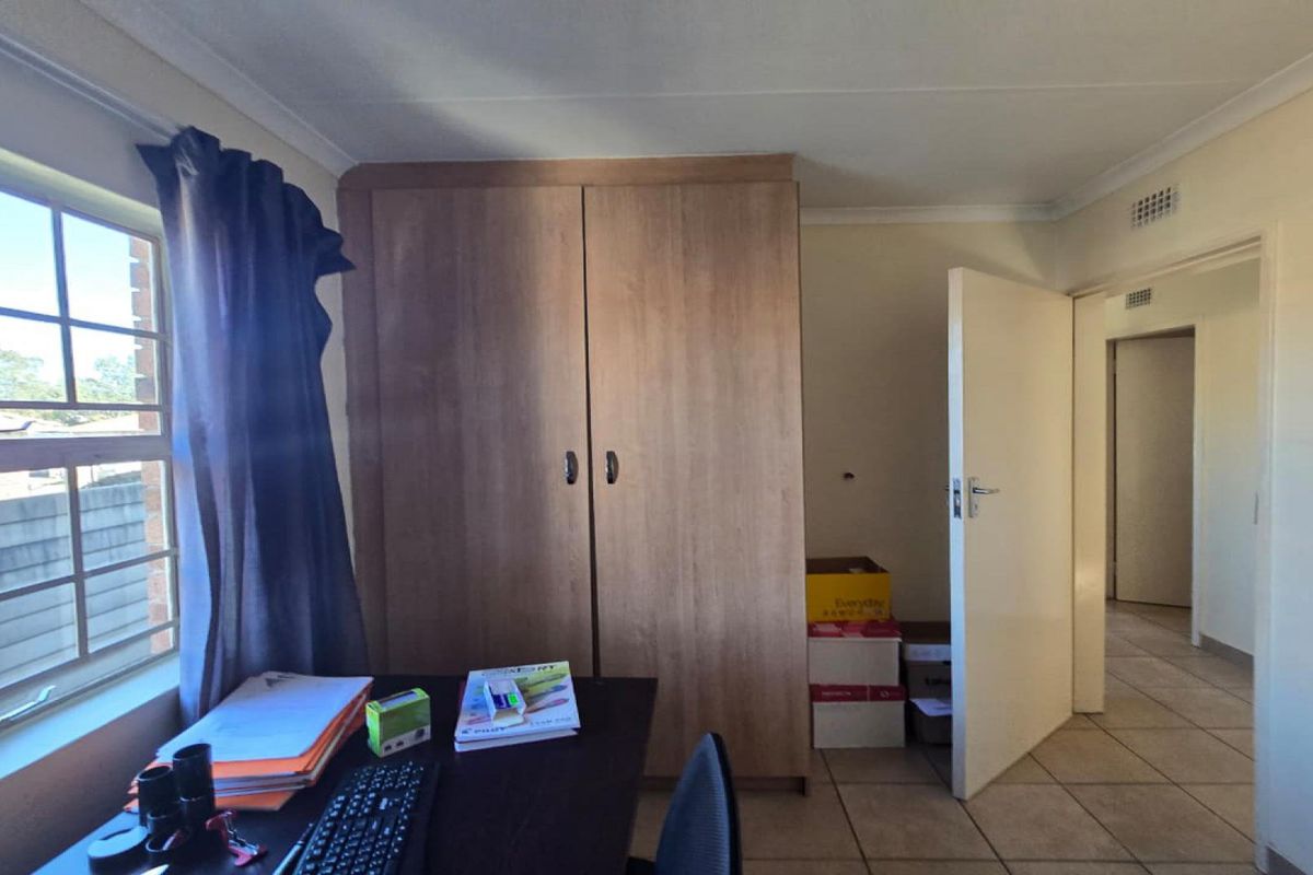 A bedroom featuring tiled flooring, a built-in wardrobe, and a window providing natural light.