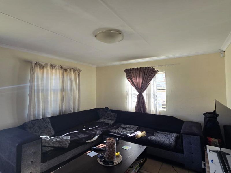 A living room featuring tiled flooring, coved ceilings, and neutral wall finishes, providing a functional space for relaxation.