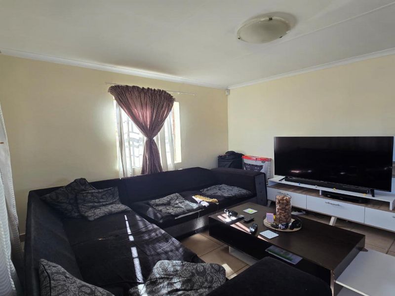 A functional living room featuring tiled flooring and coved ceiling details, providing a comfortable space for relaxation and entertainment.