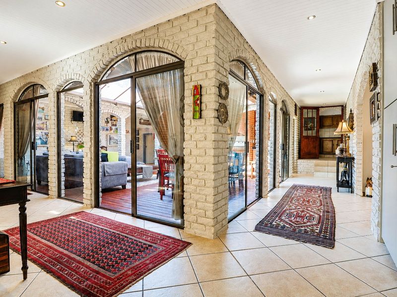 Spacious hallway featuring exposed brick walls, arched glass sliding doors providing natural light, and tiled flooring throughout.