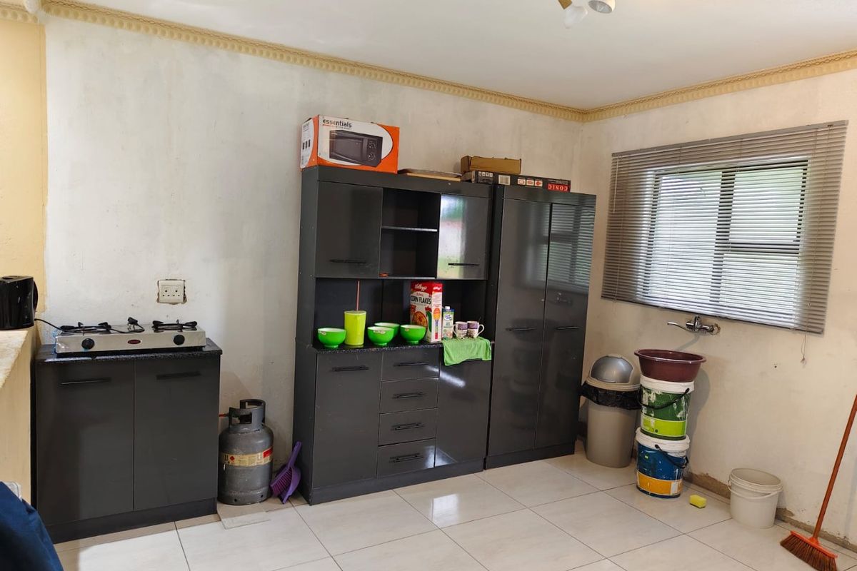 A functional kitchen area featuring dark cabinetry, a gas hob, and tiled flooring, currently requiring cosmetic updates and finishing touches to the walls.
