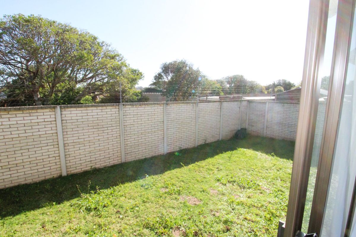 A private rear garden featuring a brick boundary wall with installed electric fencing and a grass lawn area.