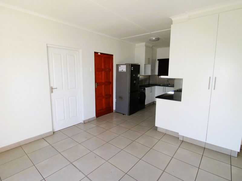 A functional kitchen area featuring tiled flooring, built-in cabinetry with stone countertops, and ample storage space.