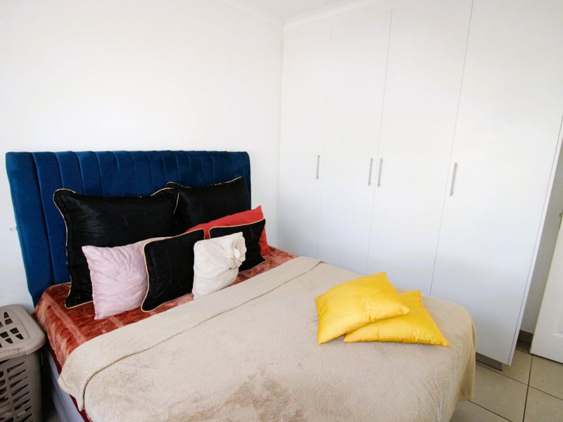 A bedroom featuring white built-in cupboards and tiled flooring, providing functional storage and a clean, neutral base for the space.